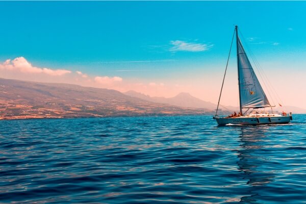 Imagem de um barco navegando em águas cristalinas com uma paisagem deslumbrante ao fundo.